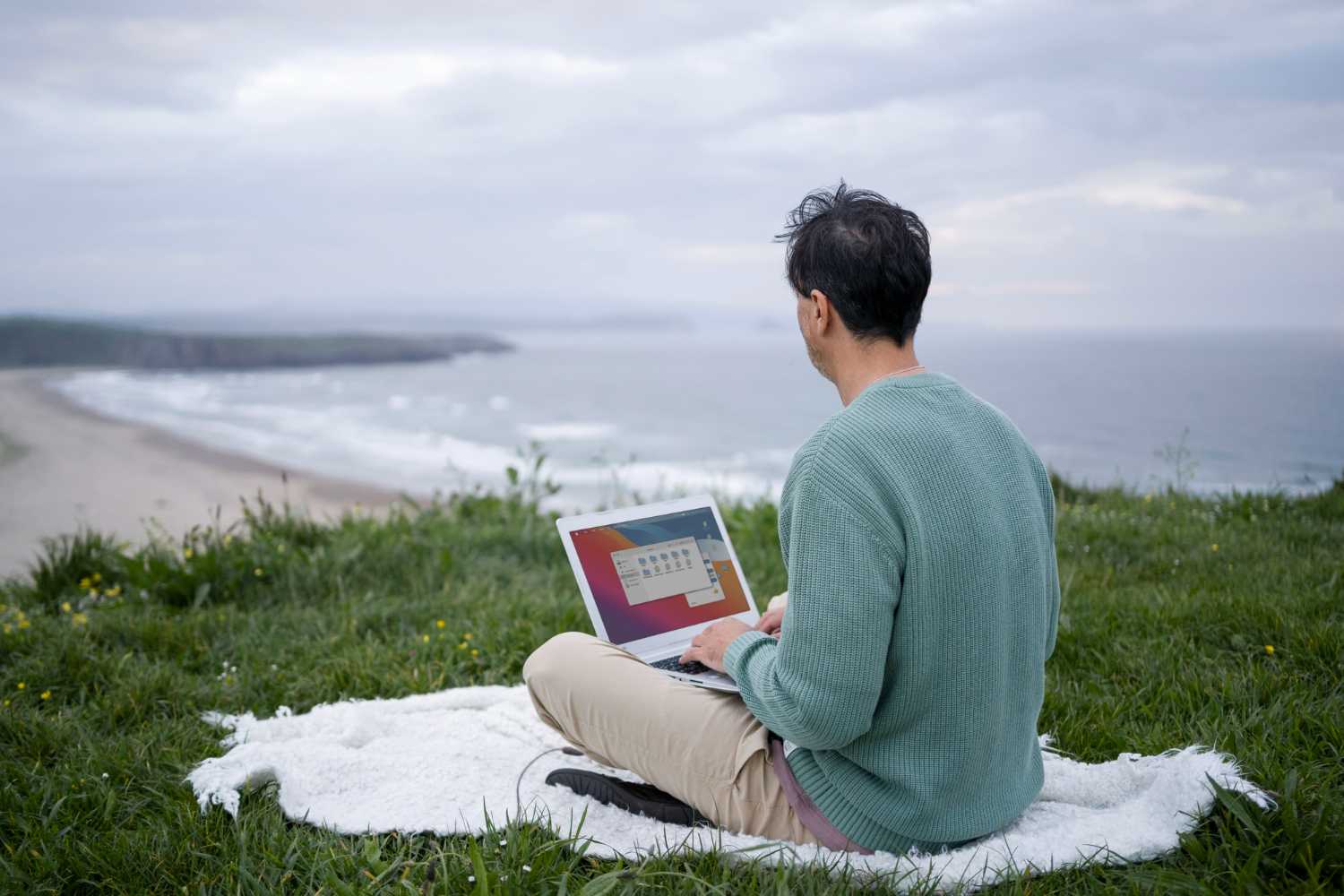 Foto de nômade digital mexendo em seu computador na praia