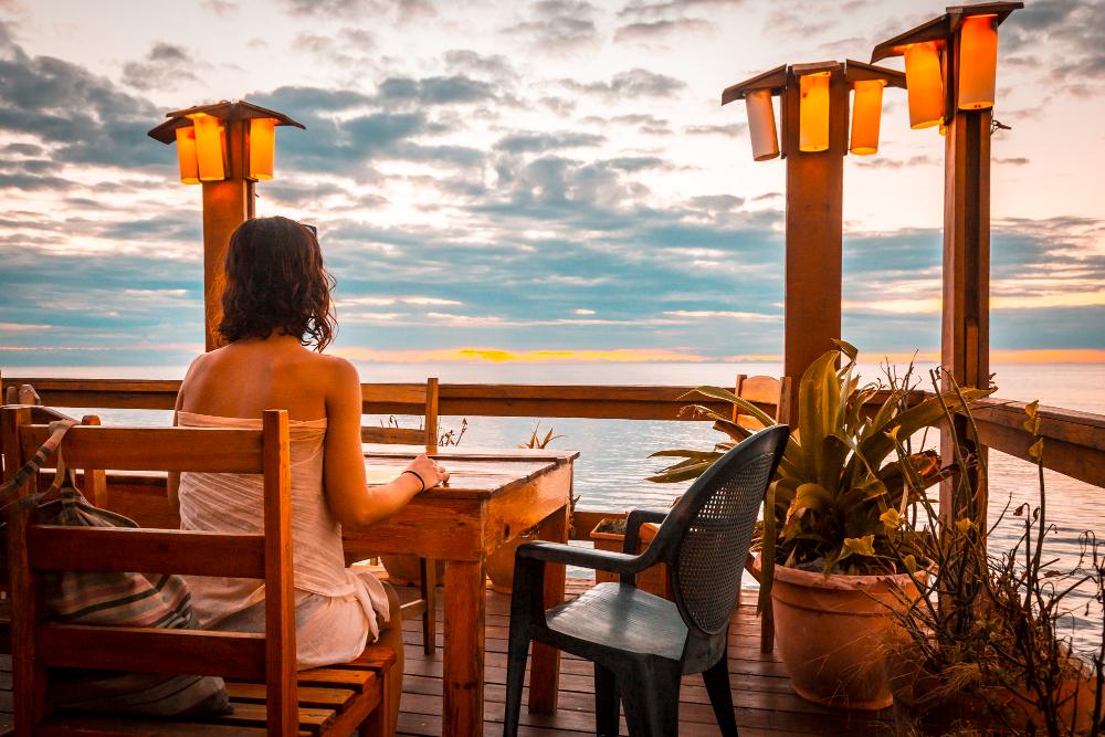 Mulher jantando em restaurante com vista para o mar